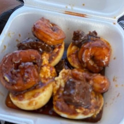 Glazed shrimp and steak in a foam takeout box
