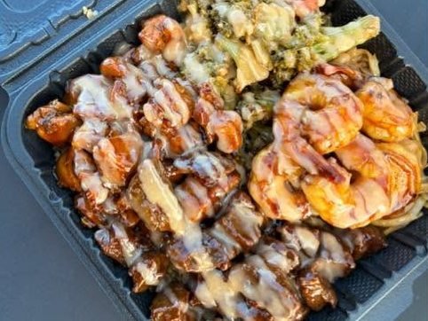 Steak bites and shrimp drizzled with yum yum sauce over noodles